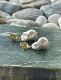 Designer Adrian Hailwood  bracelet Pearl earrings with gold clasps on a stone surface