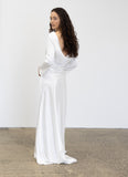 Woman wearing a fashion designer Adrian Hailwood white satin gown against a plain background